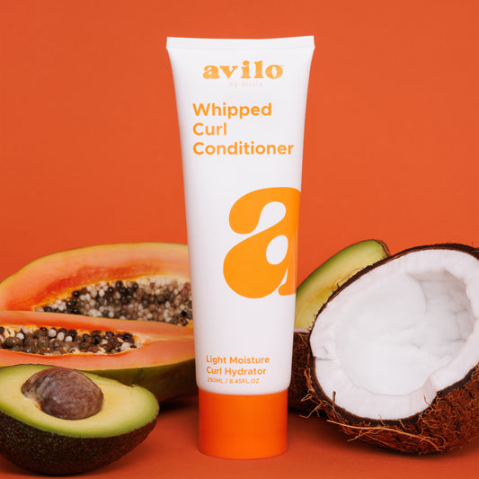 Avilo whipped curl conditioner tube with papaya, avocado, and coconut on an orange background