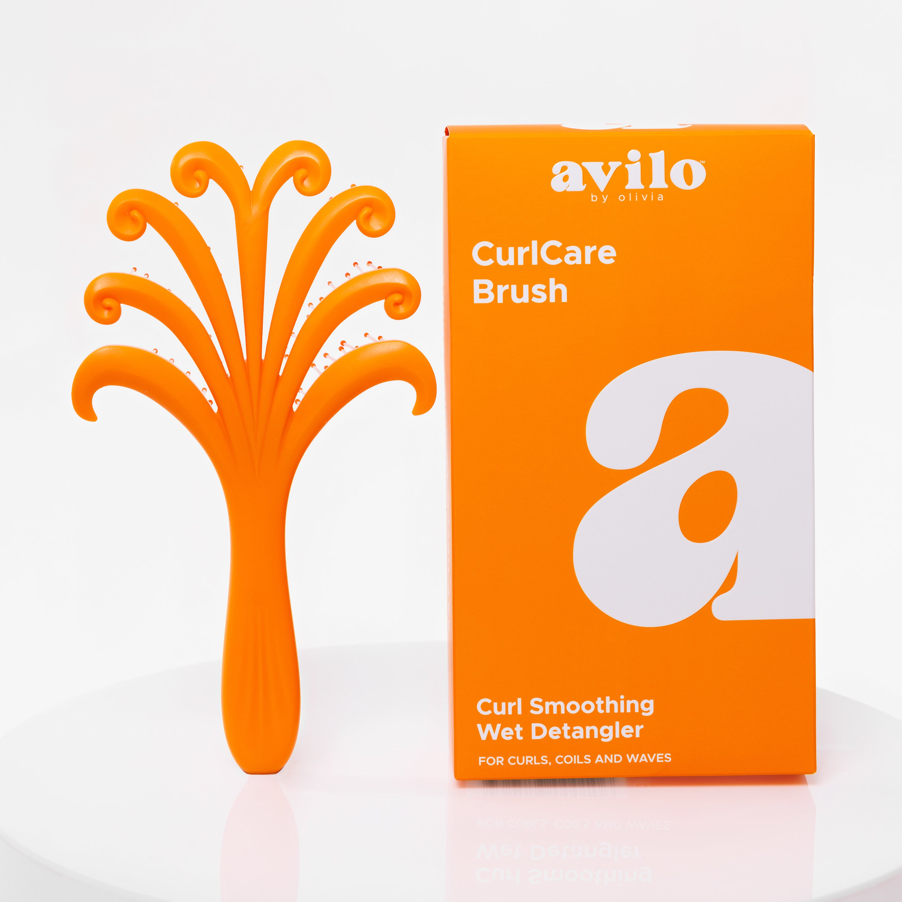 Orange curl care brush and its packaging on a white background