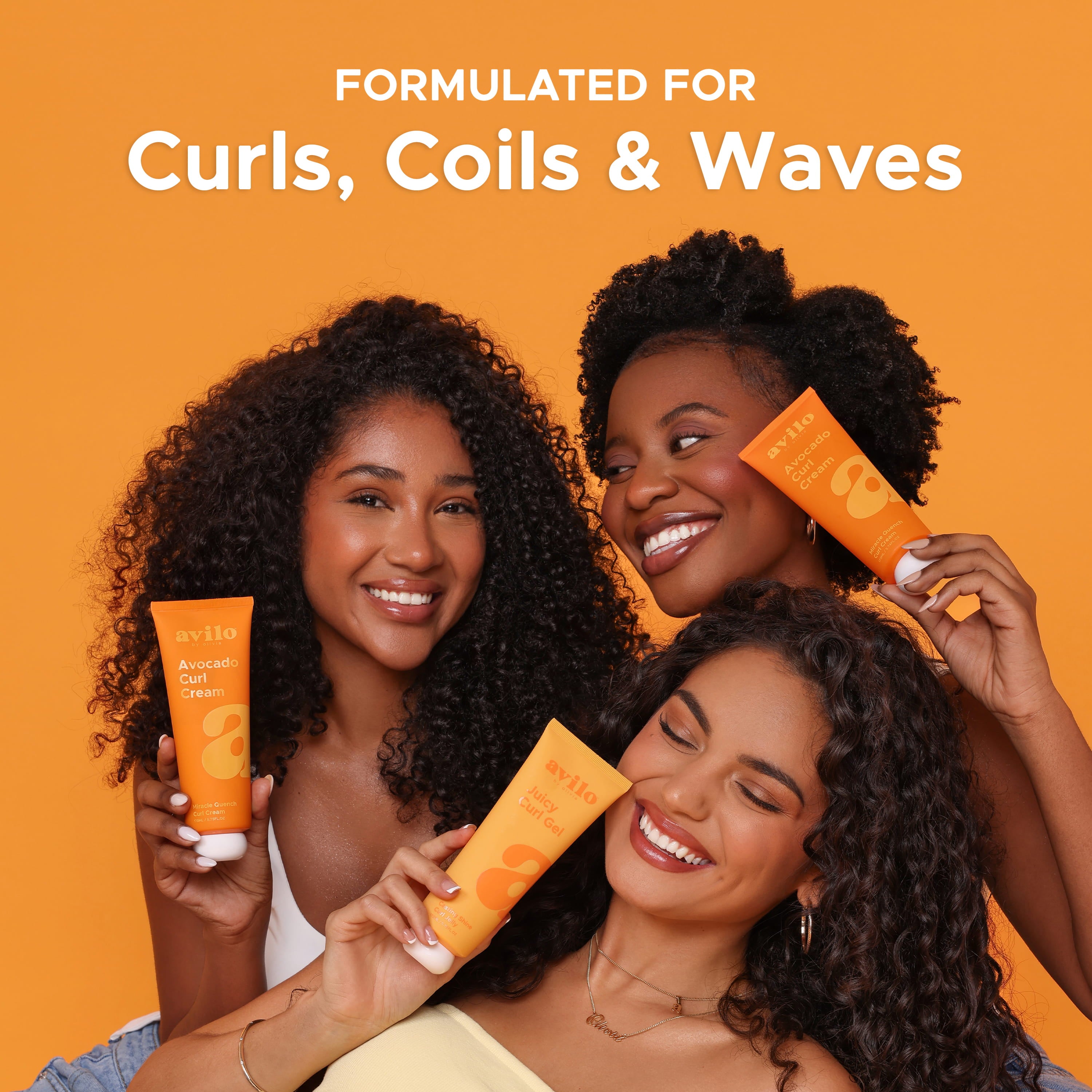 Three women with curly hair holding orange hair care products against an orange background