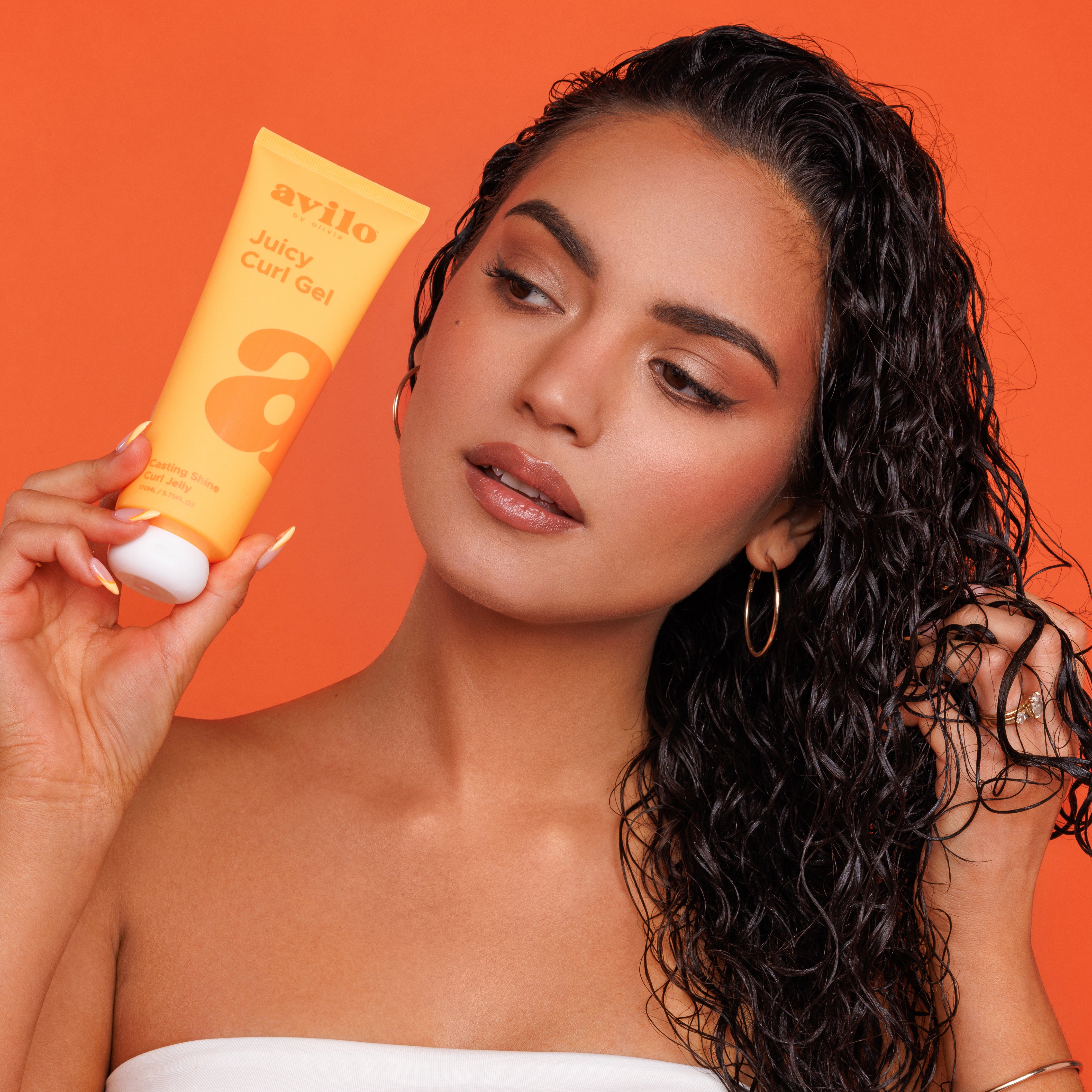 Woman holding an Avlio Juicy Curl Gel against an orange background