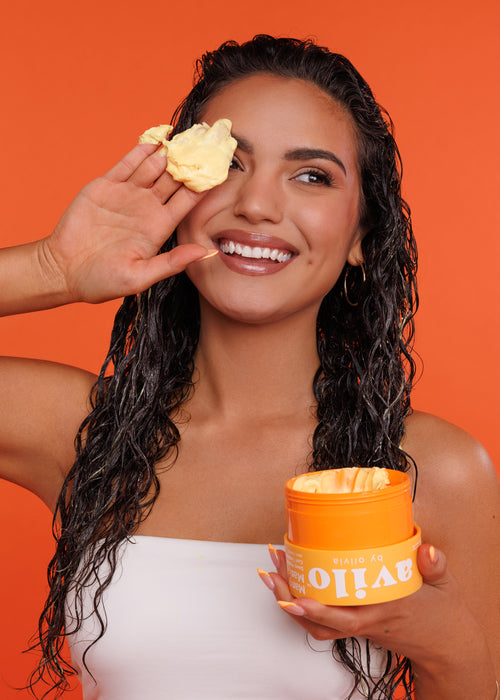 Woman applying a product to her face with an orange background