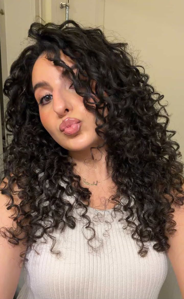 Person with curly hair sticking out their tongue indoors

