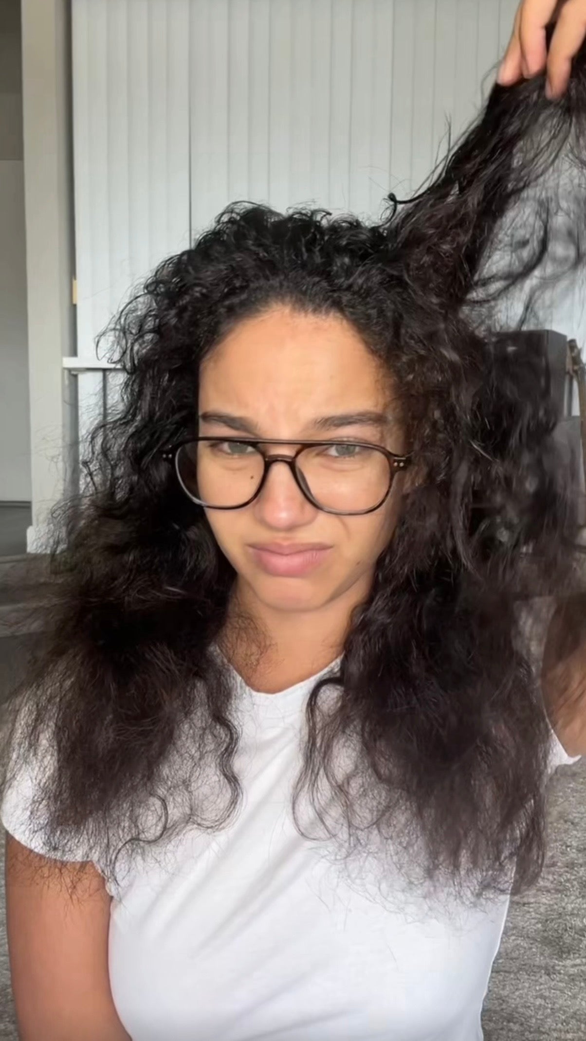 Person with long, wavy hair wearing glasses and a white shirt.