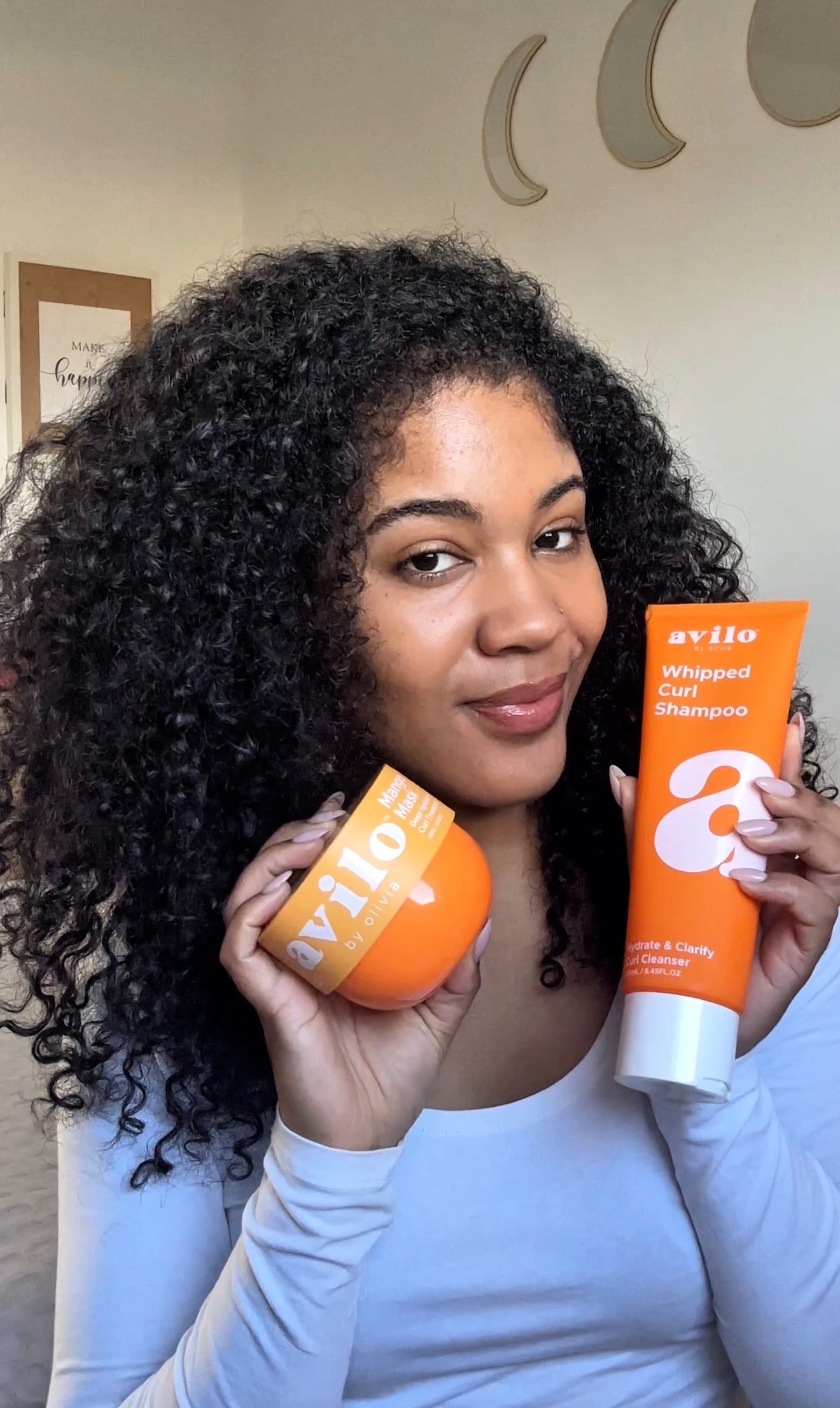 Woman holding two bottles of avivo shampoo and conditioner.