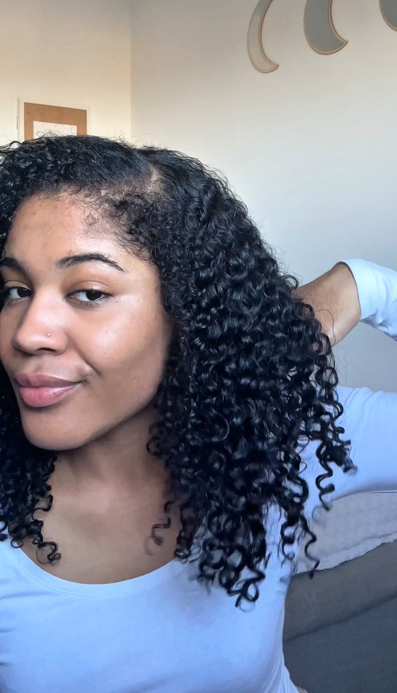 Woman with curly hair wearing a light blue shirt indoors.