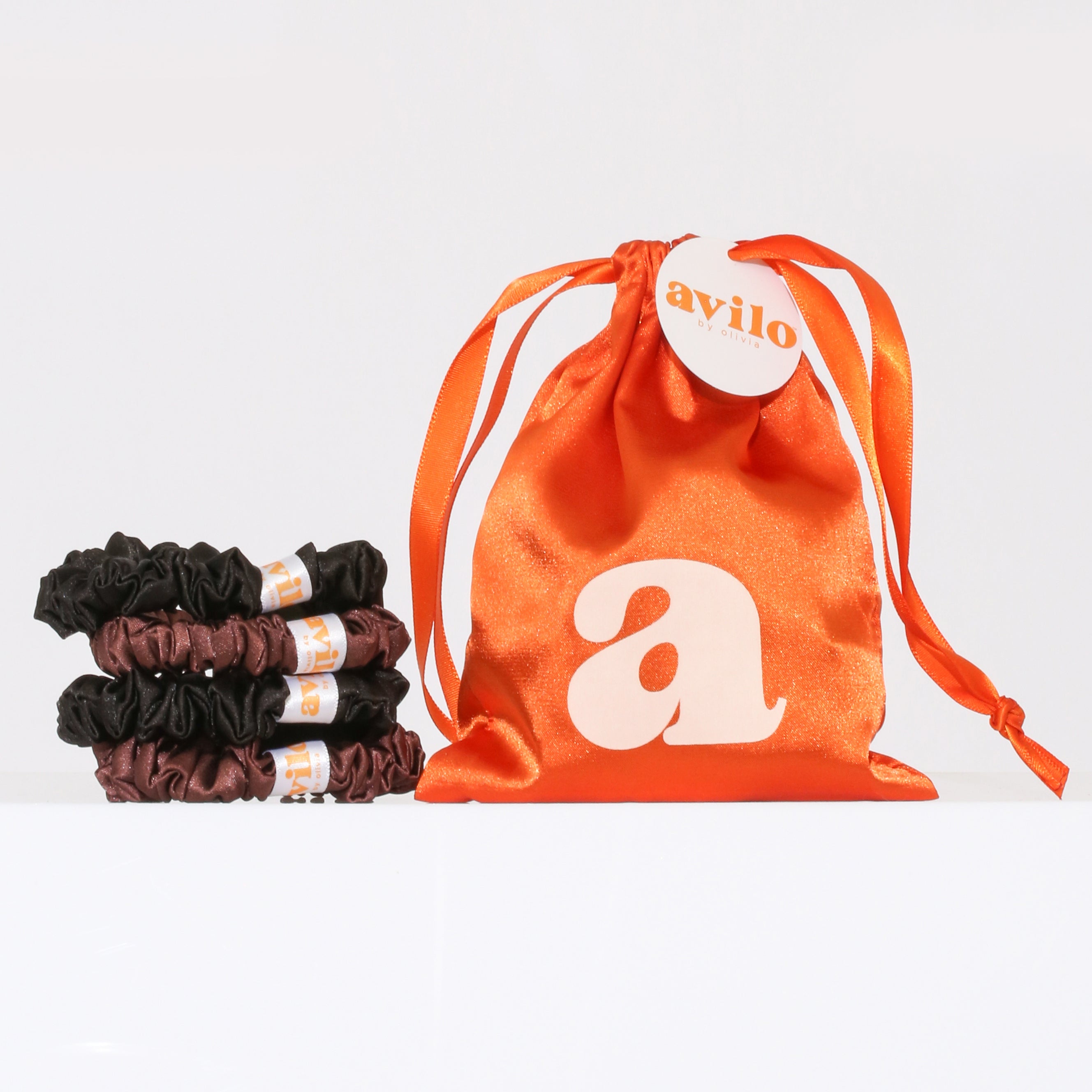 Orange drawstring bag with 'avilo' branding next to black hair ties on a white background