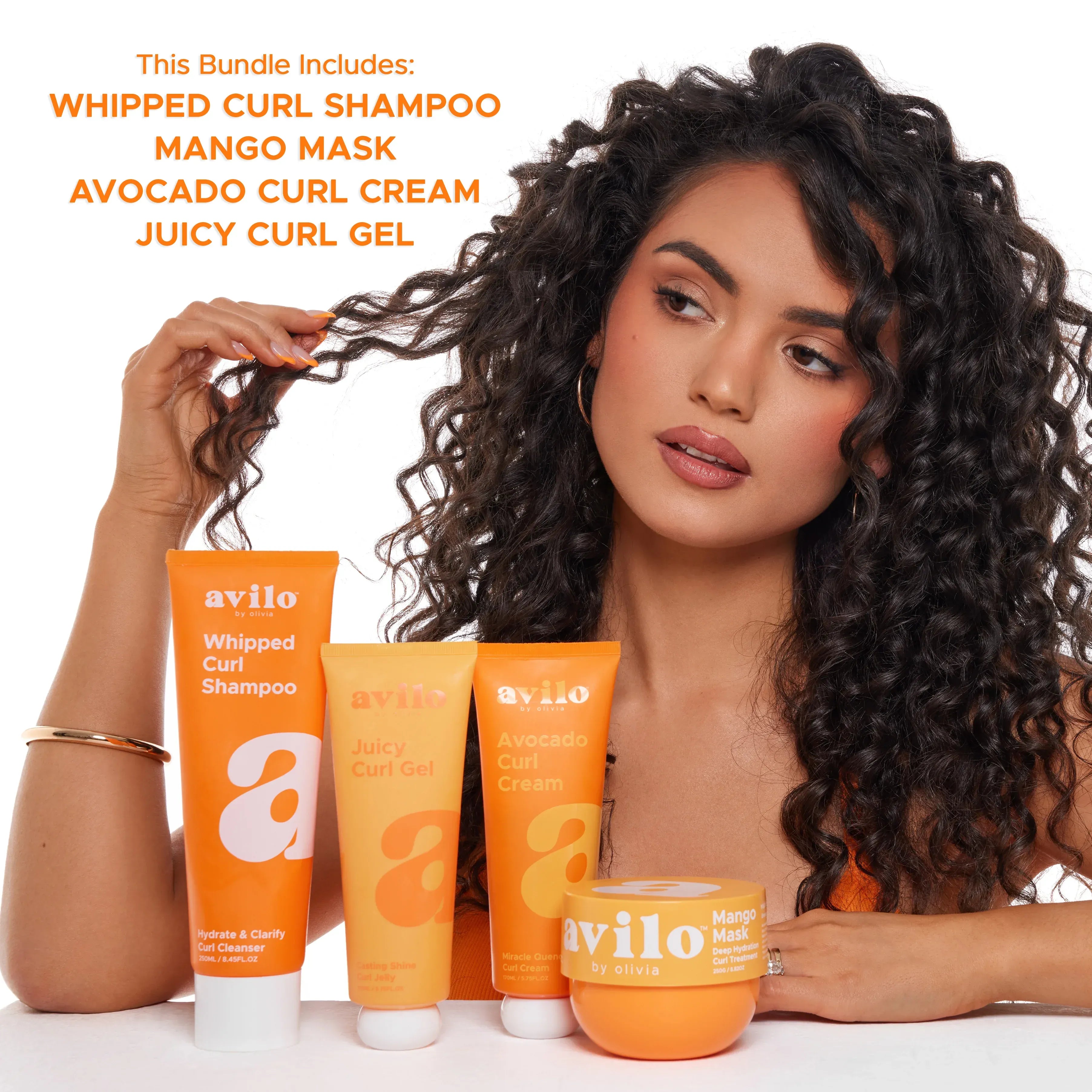 Woman with curly hair holding her hair next to Avilo hair care products on a white background

