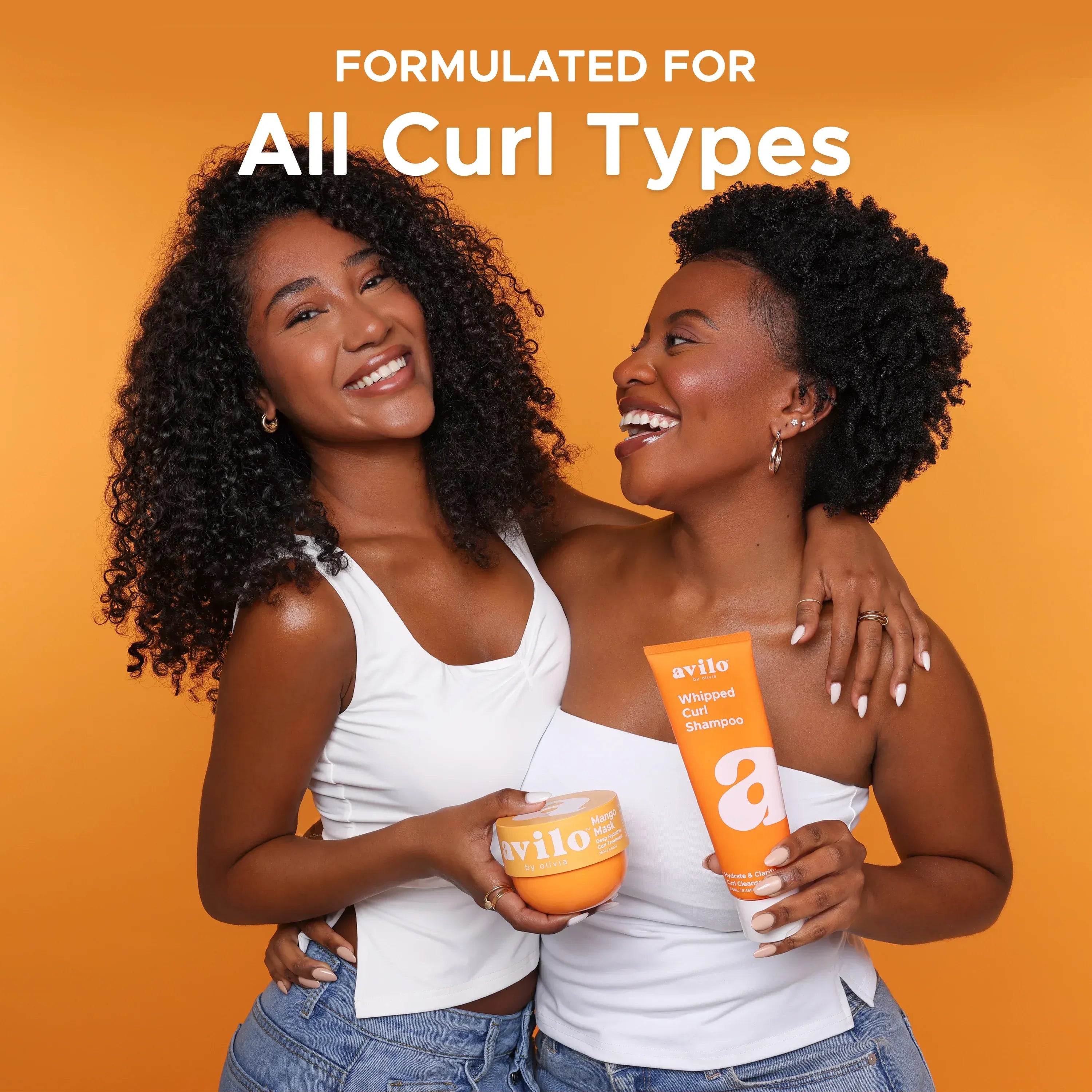 Two women with curly hair holding avila products against an orange background
