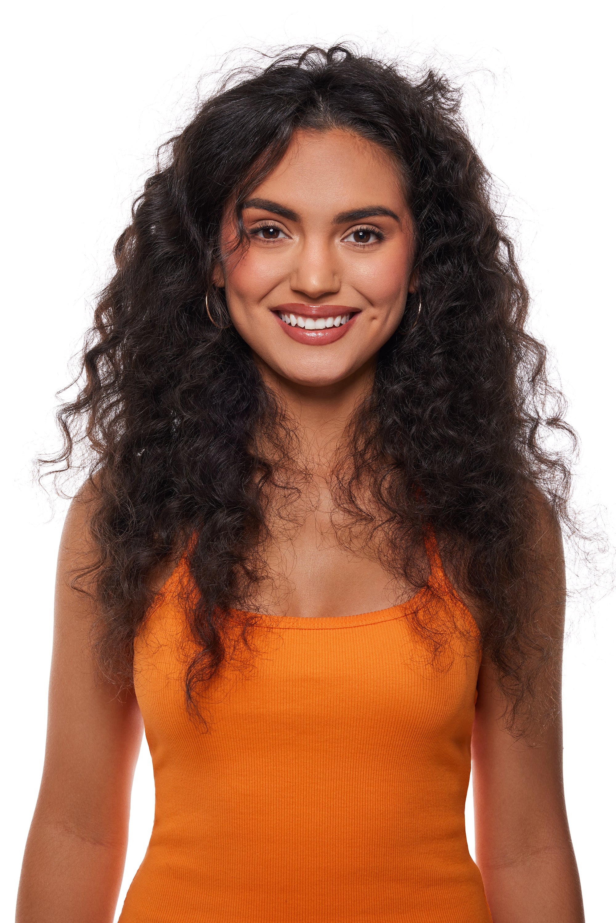 Woman with long, curly hair wearing an orange top on a white background
