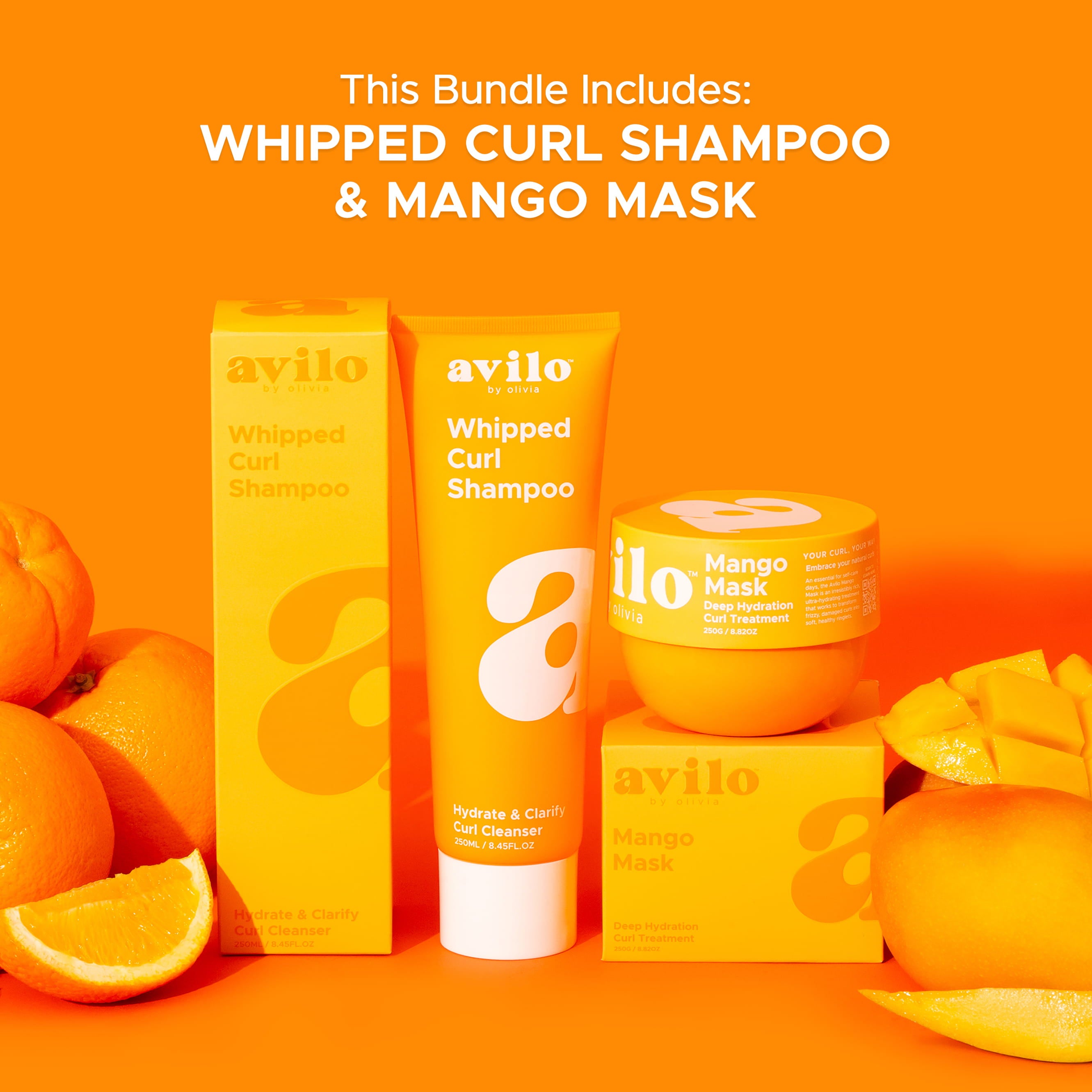 Avilo whipped curl shampoo and mango mask products on an orange background with oranges and mangoes.