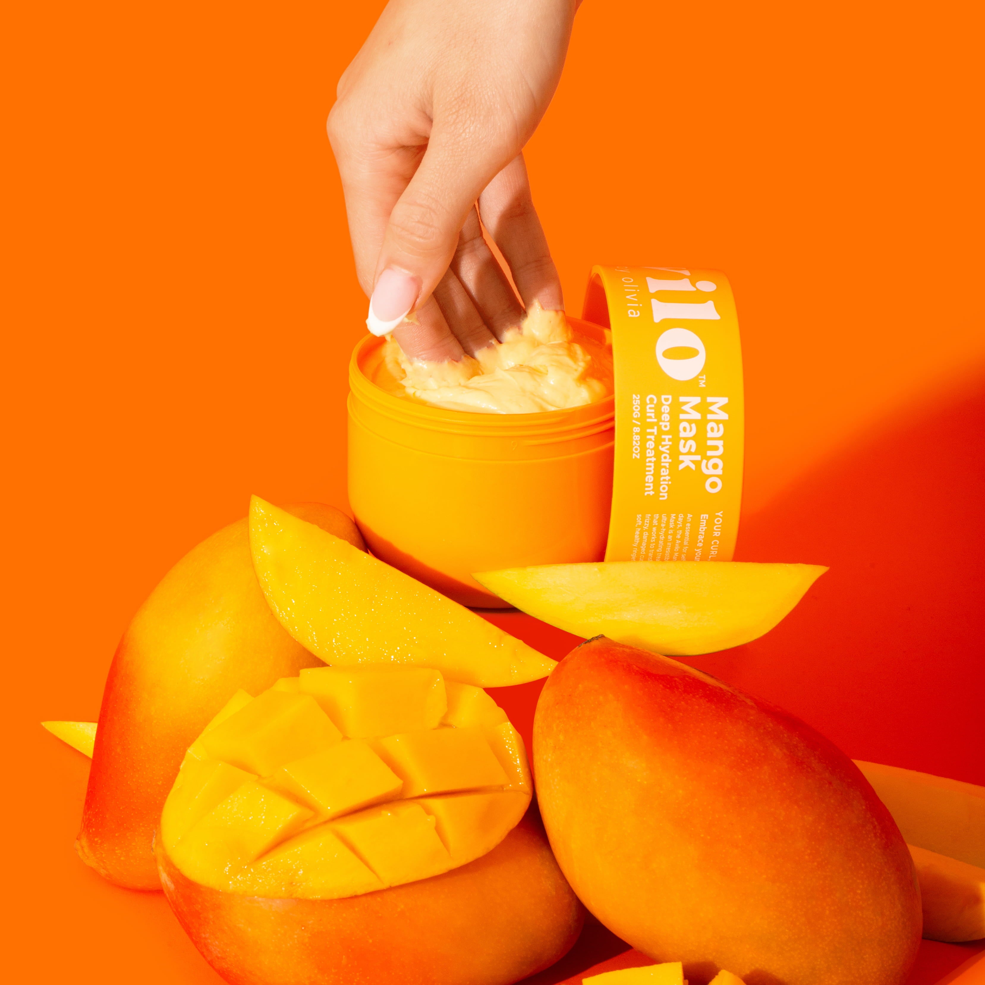 Hand interacting with a mango-themed skincare product against an orange background